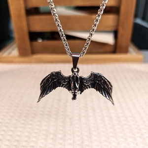Macro d'un pendentif d'ange déchu en acier inoxydable rétro avec une chaîne d'épis de blé