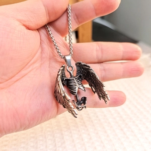 Detailed close-up of retro silver skeleton wings pendant with intricate bone textures