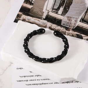 Detail of black stainless steel woven mesh bracelet with spherical ends on a white stone base