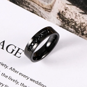 Bague minimaliste en acier inoxydable noir sertie de pierres noires sur fond de magazine