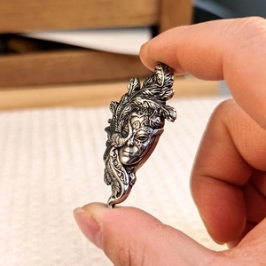 Macro shot of vintage silver tribal mask pendant with intricate feather details