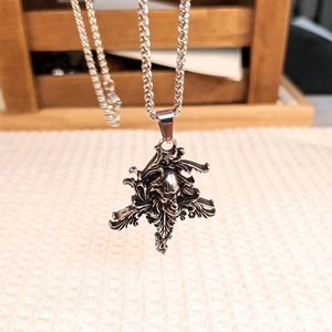 Close-up of vintage gothic skull pendant with intricate leaf details on a braided chain