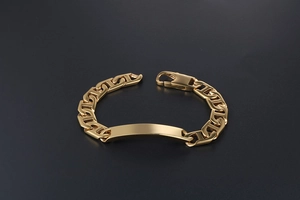 Detailed macro view of the gold-plated anchor chain bracelet and rectangular ID plate