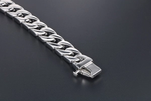 Macro view of polished stainless steel Cuban link bracelet with secure box clasp mechanism