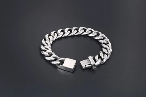 Close-up of polished silver Cuban link bracelet with flat chain and secure box clasp