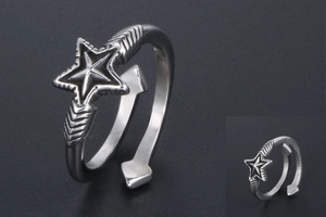 Close-up of vintage silver open ring featuring star and arrow patterns with aged finish