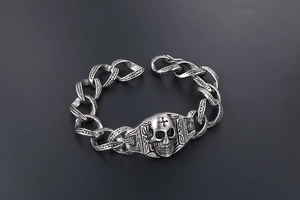 Détail macro du bracelet tête de mort rock avec maillons gravés en acier vintage poli
