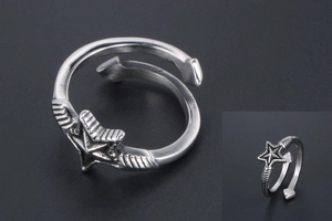 Macro detail of vintage silver star ring featuring embossed wing textures and open band