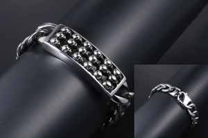 Dettaglio del bracciale punk con teschi in acciaio lucido e chiusura a moschettone