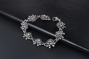 Macro shot of silver vintage stainless steel rose flower bracelet links on black leather