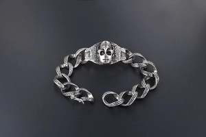 Détail d'un bracelet gourmette punk vintage avec un relief de crâne gothique et croix