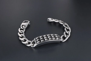 Dettaglio ravvicinato della piastra con teschi punk su bracciale a catena in acciaio argento