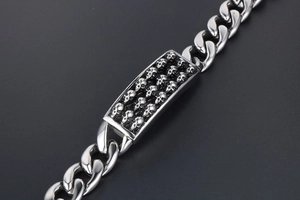Dettaglio macro del bracciale punk a catena cubana in acciaio inox con teschi in 3D