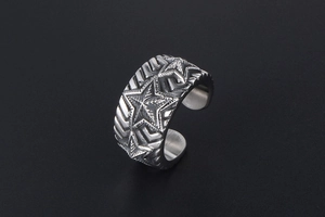 Macro detail of wide stainless steel ring with embossed stars and vintage silver finish