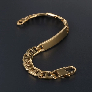 Gold-plated stainless steel chain bracelet with polished ID bar on a black surface