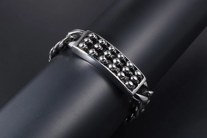Dettaglio del bracciale punk in acciaio inossidabile con incisione a teschio e catena a maglie