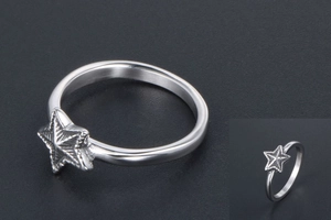 Détail d'une bague en acier inoxydable avec étoile argentée et textures sur fond sombre