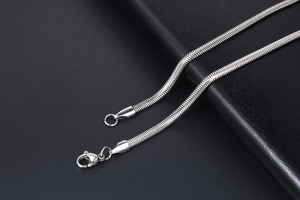 Close-up of silver snake bone chain necklace with lobster clasp on dark background