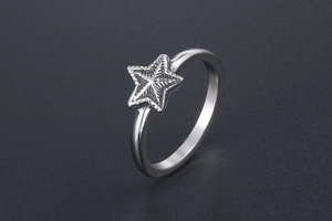 Détail macro d'une bague en acier argenté avec une étoile aux gravures radiales fines