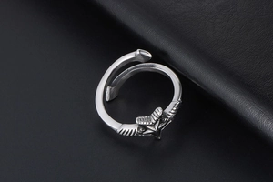 Detail of vintage silver adjustable open ring featuring star and wing carvings on black leather
