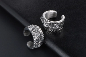 Detailed close-up of retro silver stainless steel ear cuffs with star and tire pattern