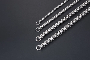 Close-up of four different thicknesses of stainless steel box chains on black background