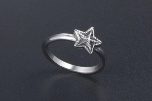 Détail d'une bague en acier inoxydable argenté avec un motif d'étoile texturé en haut