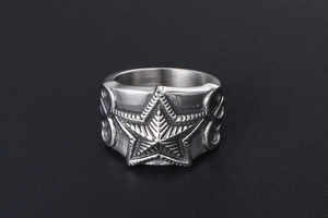 Macro detail of punk style stainless steel ring featuring a 3D star and floral patterns