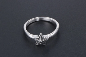 Gros plan d'une bague en acier inoxydable avec une étoile 3D sur fond noir