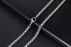 Detail shot of high-polish silver box chain necklace with lobster clasp on black background