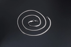 Detailed macro view of a silver snake chain necklace with a secure lobster clasp