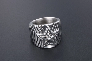 Vue macro d'une bague large en acier inoxydable argenté avec étoile en relief texturée