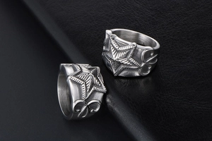 Macro shot of stainless steel star rings with wave engraving on black leather background