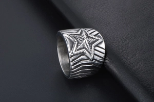 Détail macro d'une bague large pour homme en acier avec relief étoile sur cuir noir