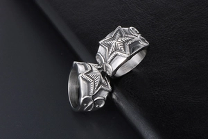 Detailed view of silver punk star rings with vintage engravings on black leather texture