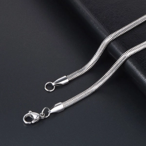 Polished silver snake bone necklace chain with lobster clasp on black leather background