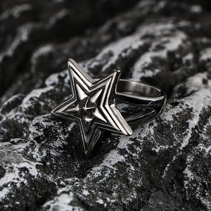 Vintage oversized star ring in polished titanium steel on a dark volcanic rock background