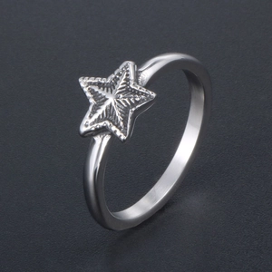 Bague étoile en acier inoxydable avec texture radiale sur un fond sombre minimaliste
