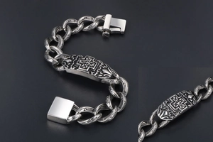 Macro shot of punk style stainless steel chain bracelet with embossed cross detail