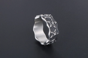 Macro shot of retro stainless steel star ring with wavy edges and vintage black finish