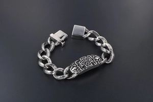Macro detail of men's chunky titanium steel bracelet with cross pattern plaque