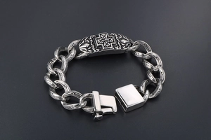 Close-up of vintage gothic cross plaque on thick stainless steel chain bracelet
