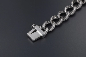 Macro view of vintage engraved Cuban chain link bracelet with polished square clasp