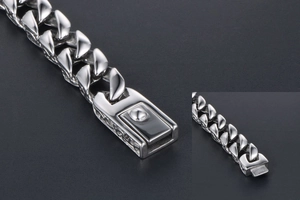 Macro detail of silver stainless steel Cuban link bracelet with engraved pattern clasp