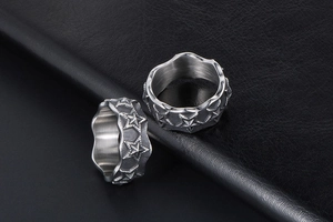 Macro shot of silver titanium rings with star patterns and wavy edges on leather