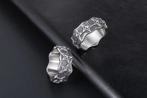 Macro shot of two vintage star-engraved steel rings with oxidized finish on black leather