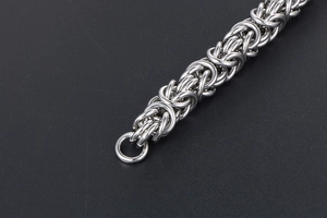 Macro shot of silver Byzantine weave titanium steel chain with complex interlocking rings