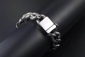 Detailed macro view of engraved cuban chain links and square clasp on silver bracelet