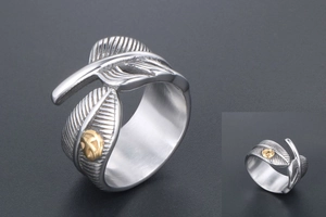 Macro shot of vintage feather ring with brushed metal texture and gold emblem detail