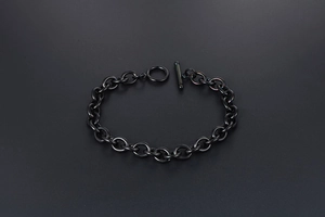 Close-up of black titanium steel chain bracelet with a toggle clasp on dark background